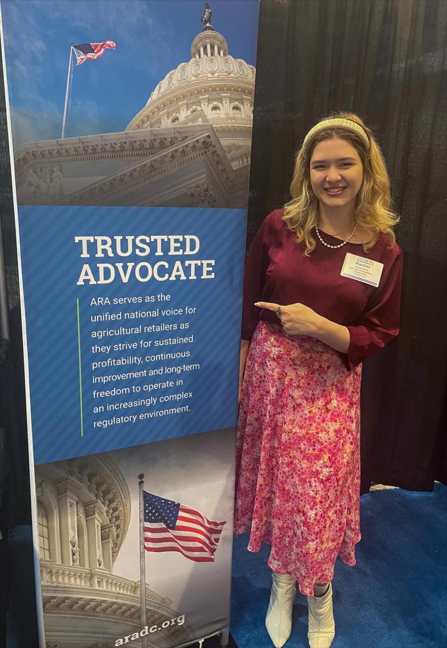 ARA Summer Intern Rachel Nelson poses with an ARA banner about advocacy for ag retailers at the InfoAg conference.