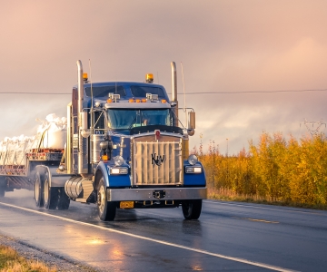Blue Semi Truck hauling a load down a road