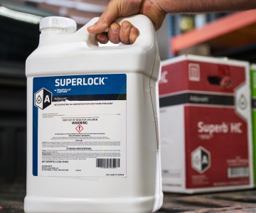 A container of SuperLock™ adjuvant sits on the tailgate of a pickup truck