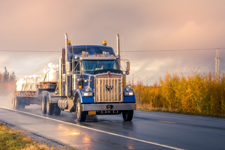 Blue Semi Truck hauling a load down a road