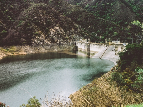 A one sided view of a dam with water and a vegetation around it