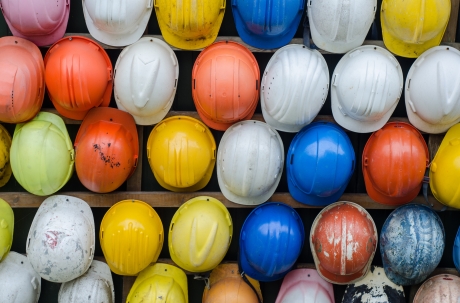 Wall of hard hats of all colors hanging up 
