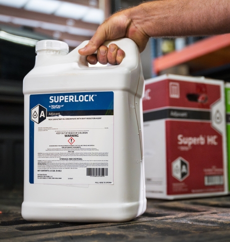 A container of SuperLock™ adjuvant sits on the tailgate of a pickup truck